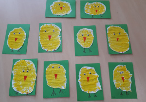 Plastykoterapia w grupie 1. Na zdjęciu namalowane żółtą farbą kurczaki, wycięte i naklejone na zielony karton.